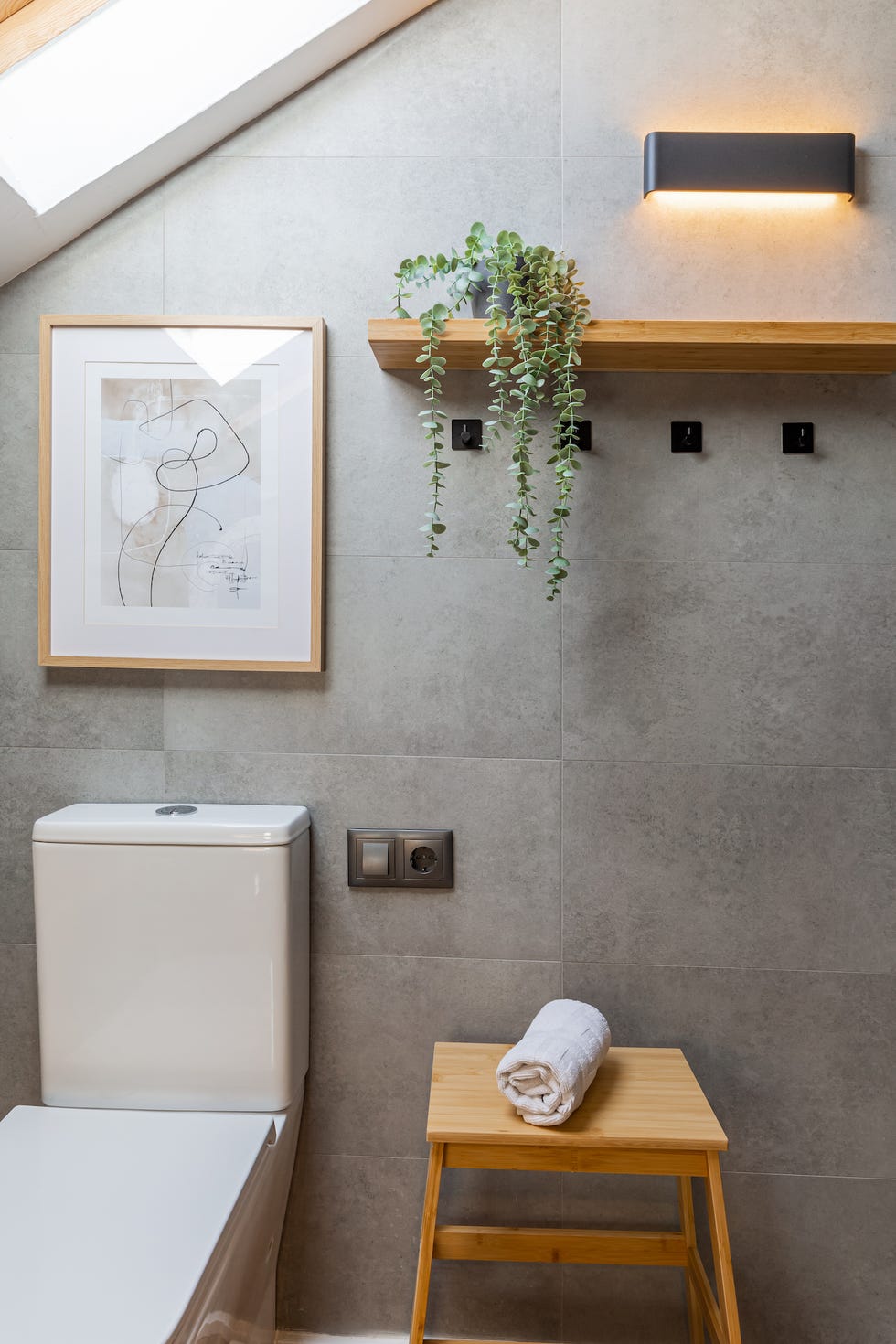 baño con paredes de efecto microcemento y estante de madera
