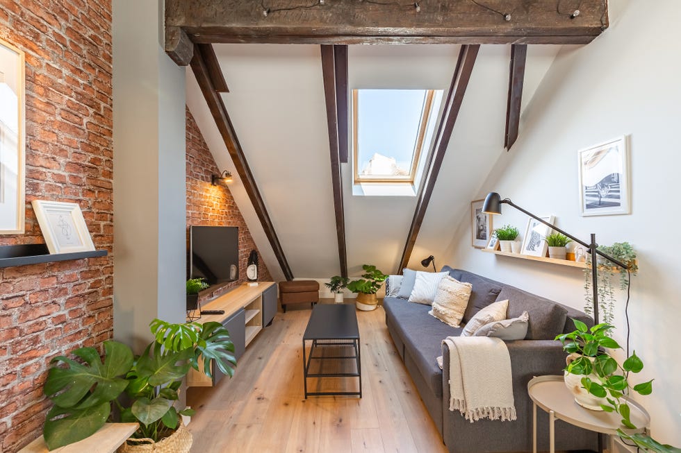 salón con sofá gris y pared de ladrillo visto