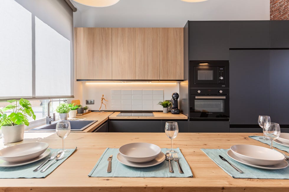 cocina moderna con barra de madera y armarios negros sin tiradores