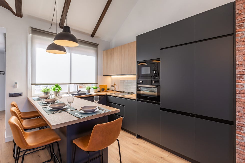 cocina moderna con barra de madera y armarios negros sin tiradores
