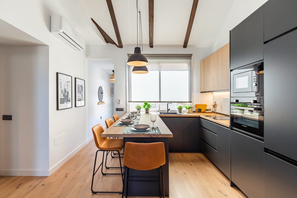 cocina moderna con barra de madera y armarios negros sin tiradores