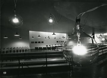 the installation at the xi triennale in milan, 1957, featuring a series of connected bulbo lamps on this occasion, the light was conceived as an interior design element