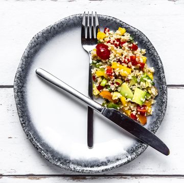 bordje met mes en vork erop, salade met verschillende groente op een deel van het bordje
