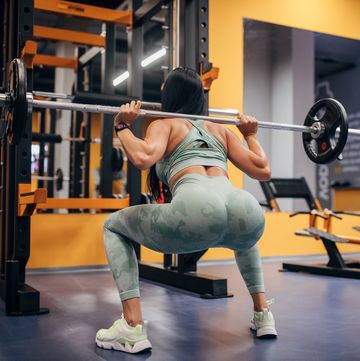 woman squatting with a weight on her back
