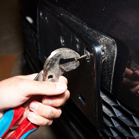 grabbing screw with pliers to remove rivet from front license plate