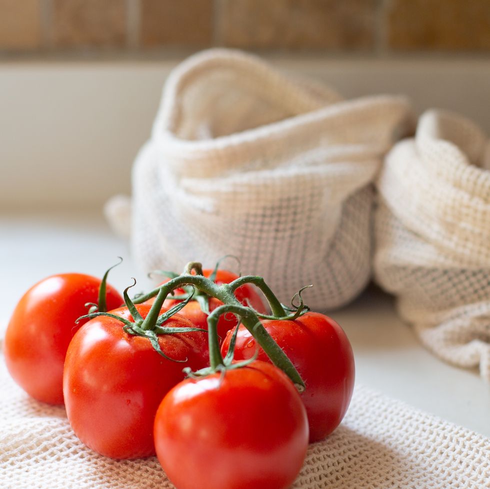bunch of tomatoes on vine with reusable produce bags