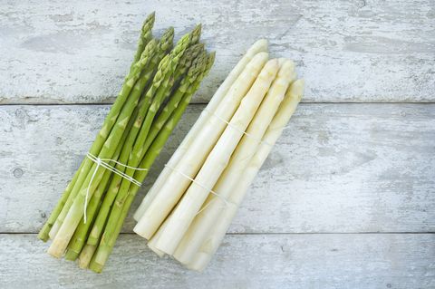 Bunches of green and white asparagus on wood