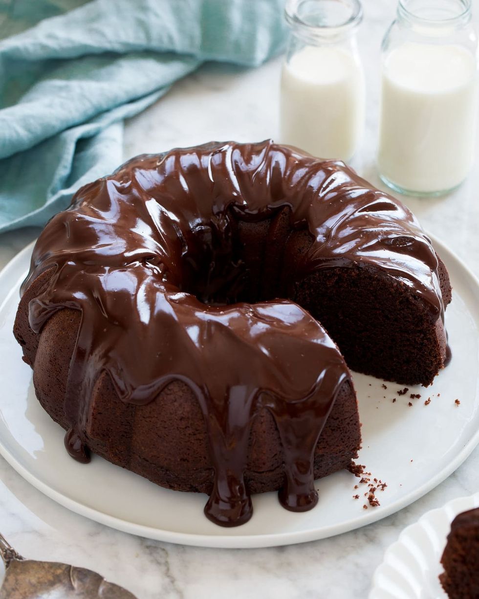 chocolate bundt cake with chocolate frosting and milk jars in back