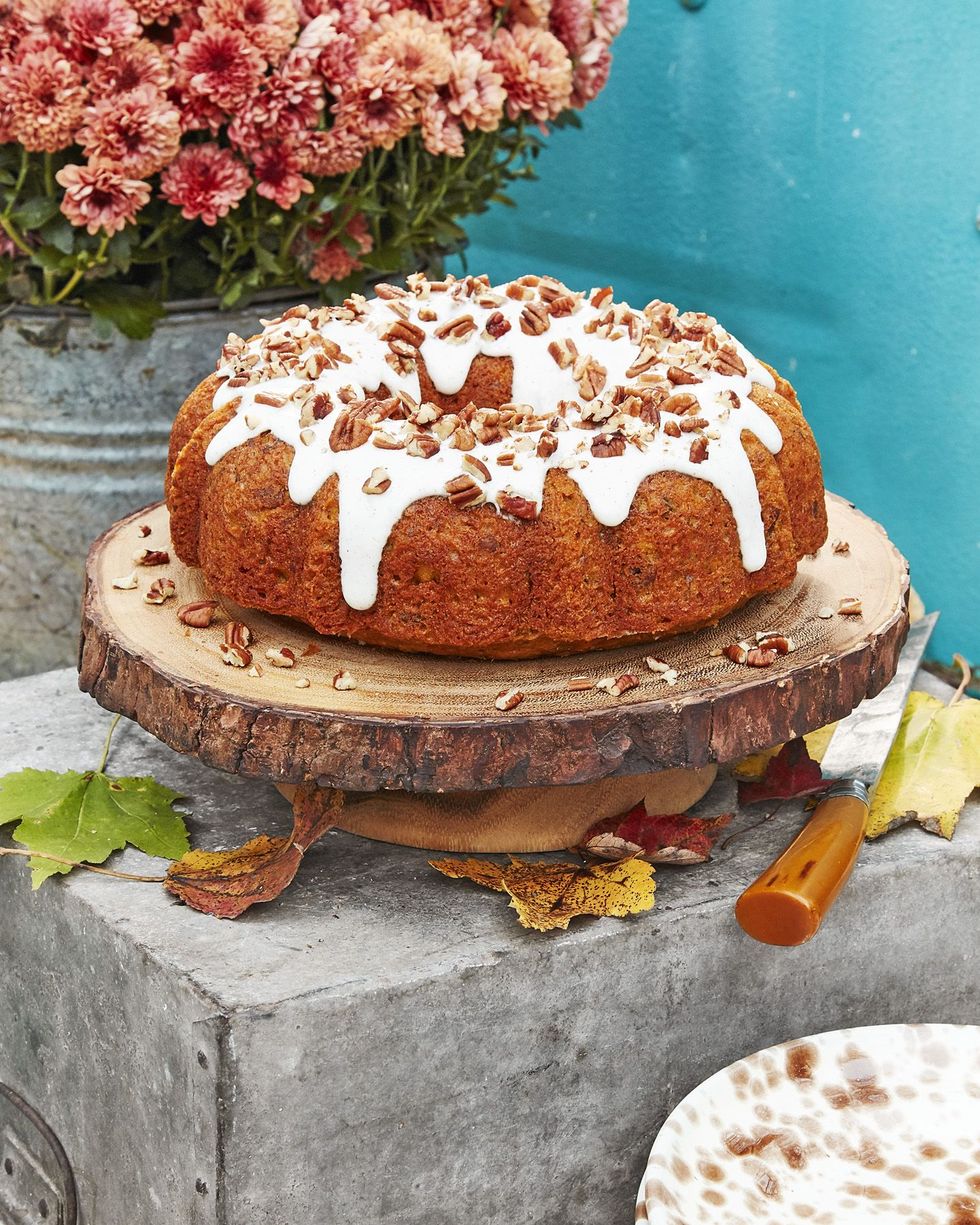 pecan pumpkin bundt cake with cream cheese glaze on a rustic tree slice platter