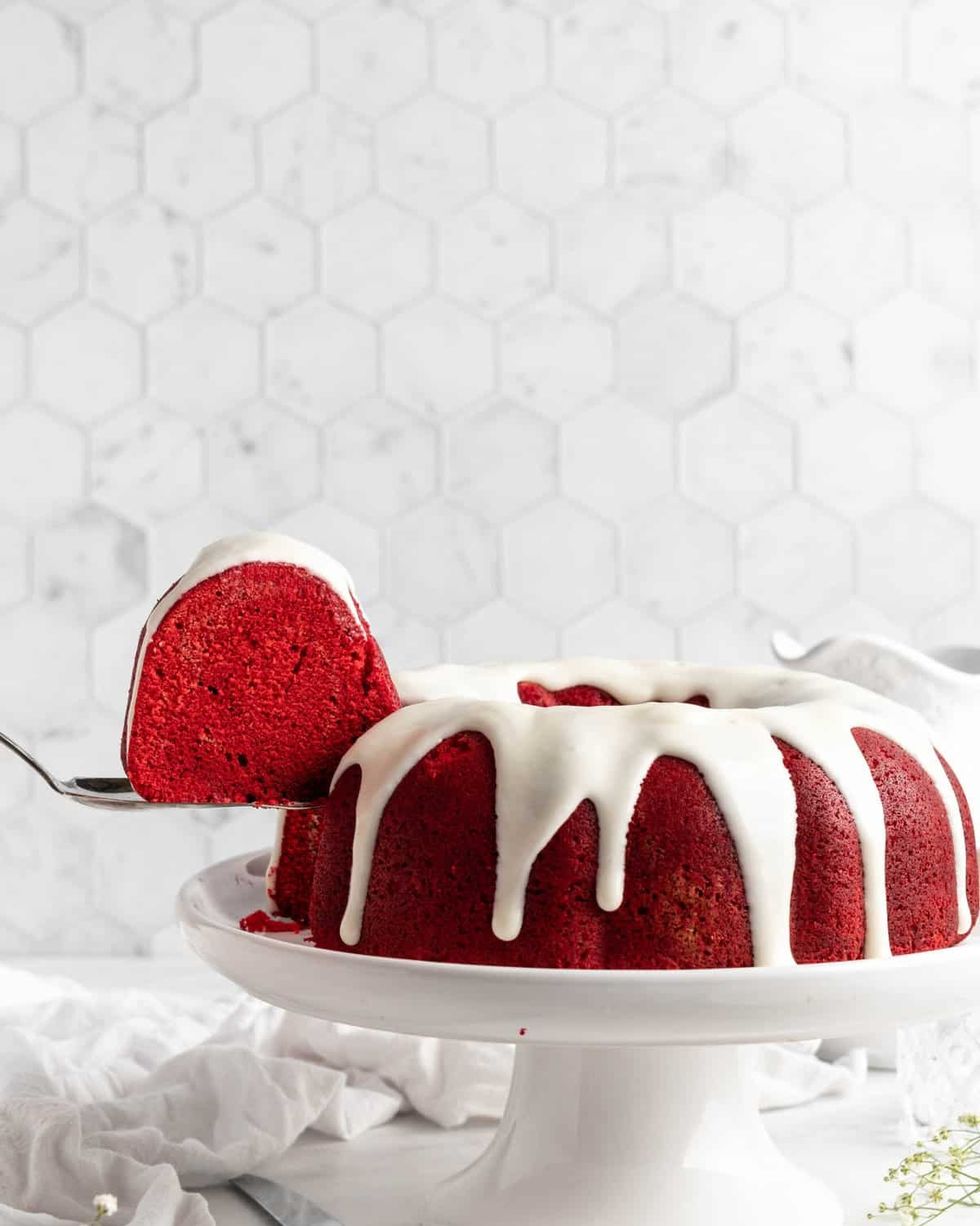 red velvet bundt cake with white frosting on white cake stand