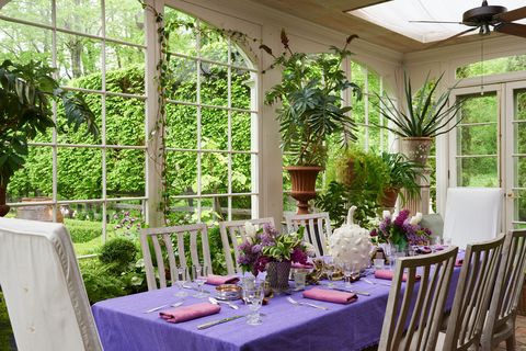 a table surrounded by greenery with purple tablecloth and pink napkins