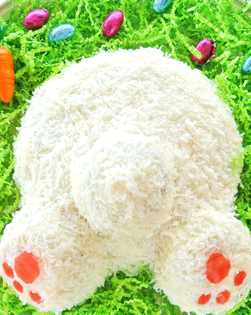 a cake shaped like a bunny butt tail and back feet on fake paper grass