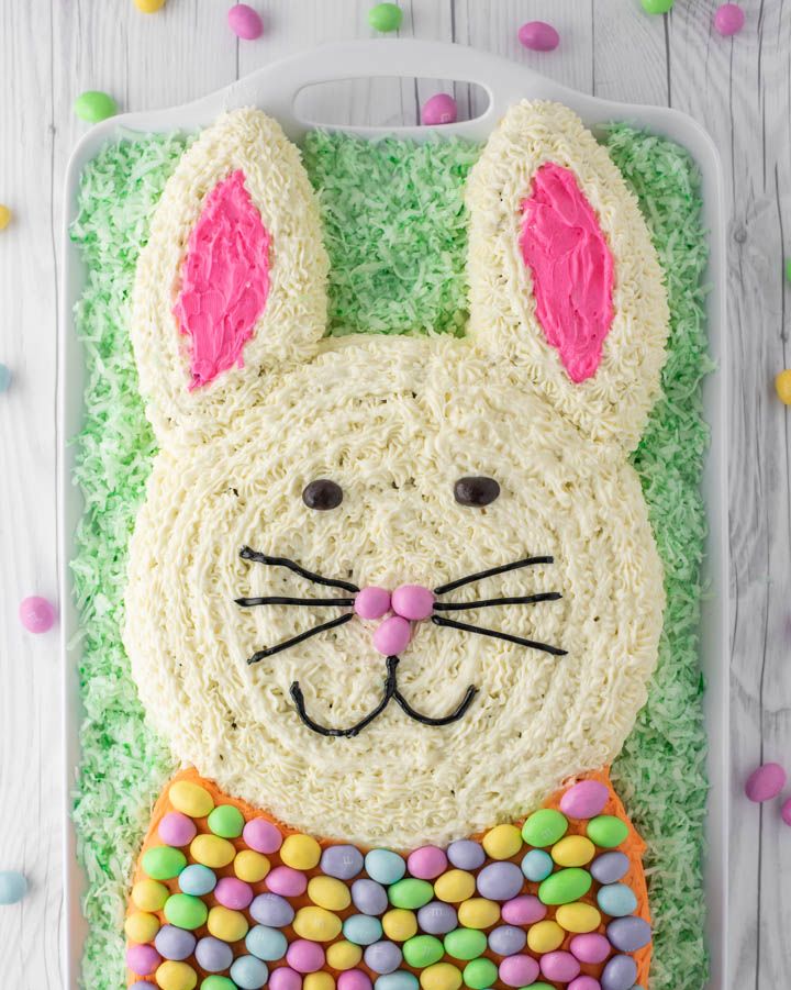 easter bunny carrot cake shaped like a bunny head with ears and a bow covered in m and m eggs