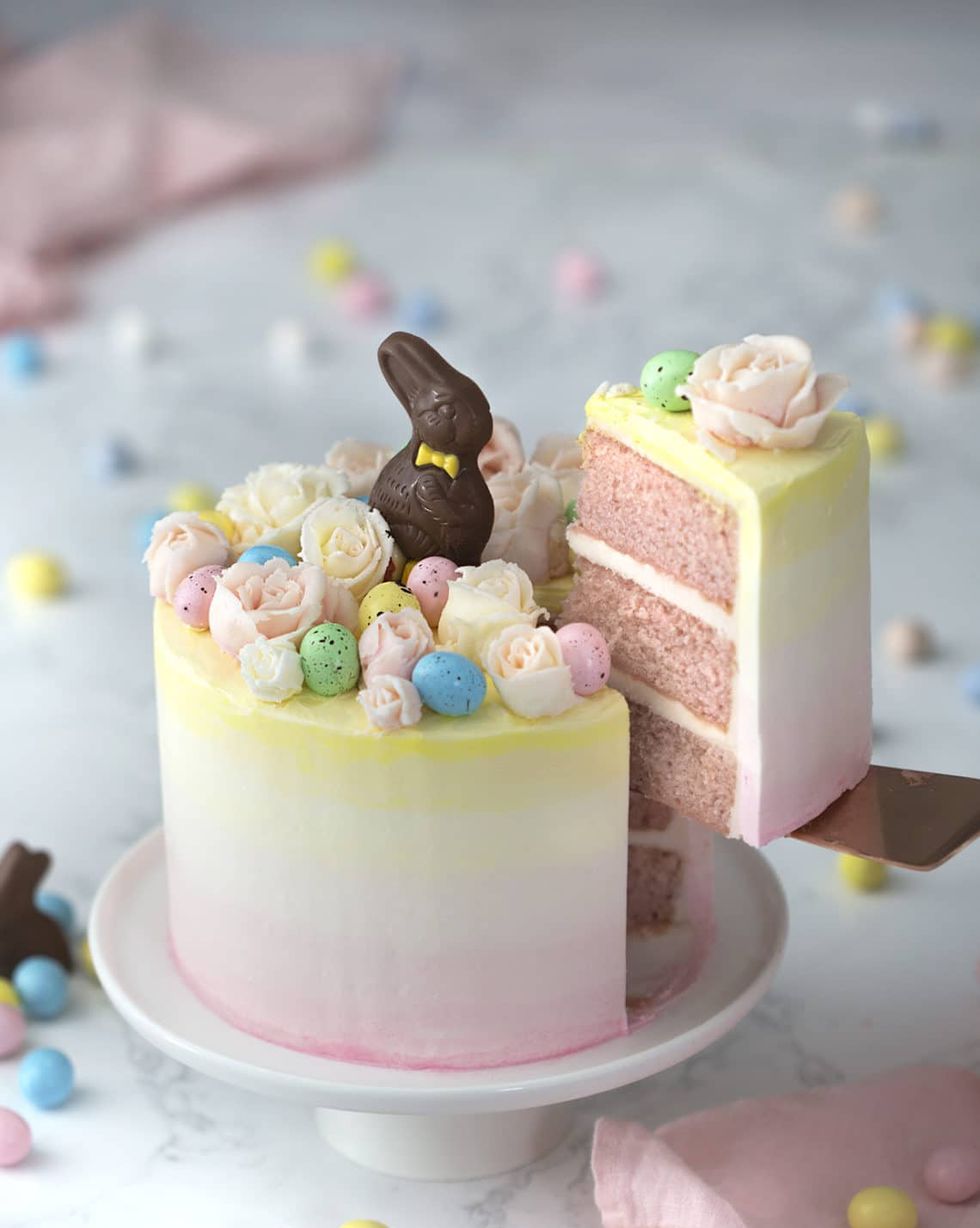 pastel pink and yellow ombre cake with speckled egg candy buttercream roses and chocolate easter bunnies on top