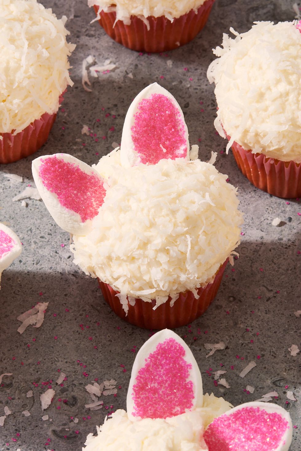 bunny cupcakes topped with white shredded coconut and marshmallow ears with pink sanding sugar