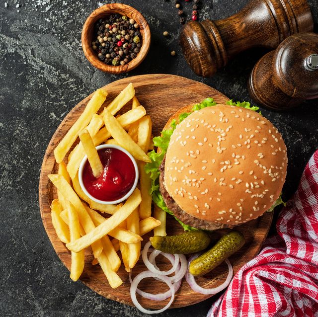 burger and fries on wooden board on dark stone background