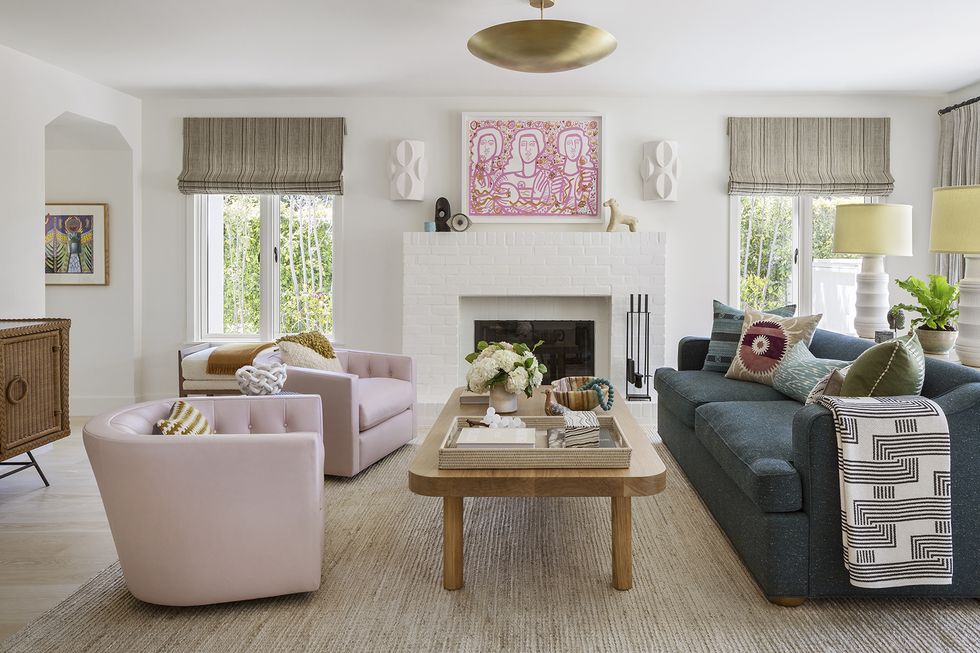 white living room with light pink armchairs and blue couch