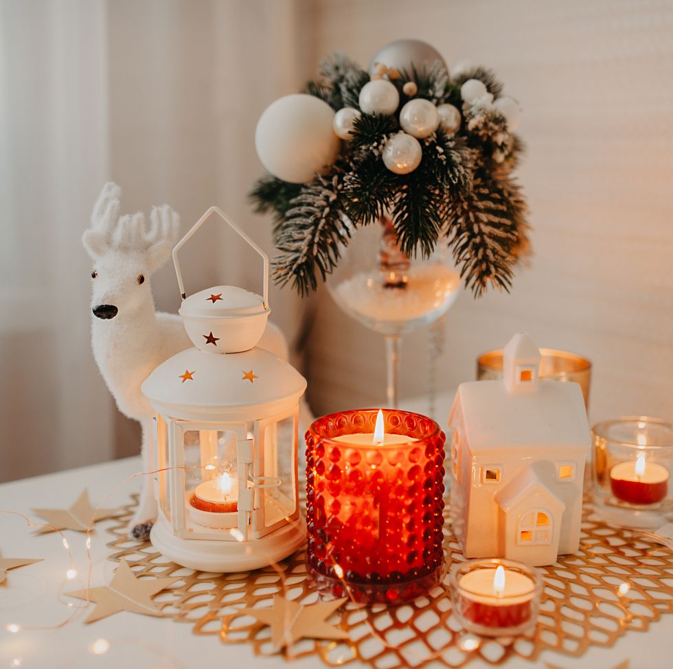 burning white and red candles, a candlestick of lantern form on napkin, figurinemoose, garlands