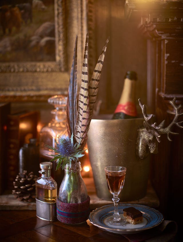 a rustic setting featuring a glass of drink flowers in a bottle and a dessert