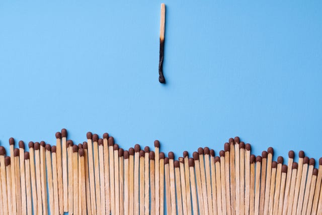 a burnt wooden match against a line of whole matches creative burnout concept