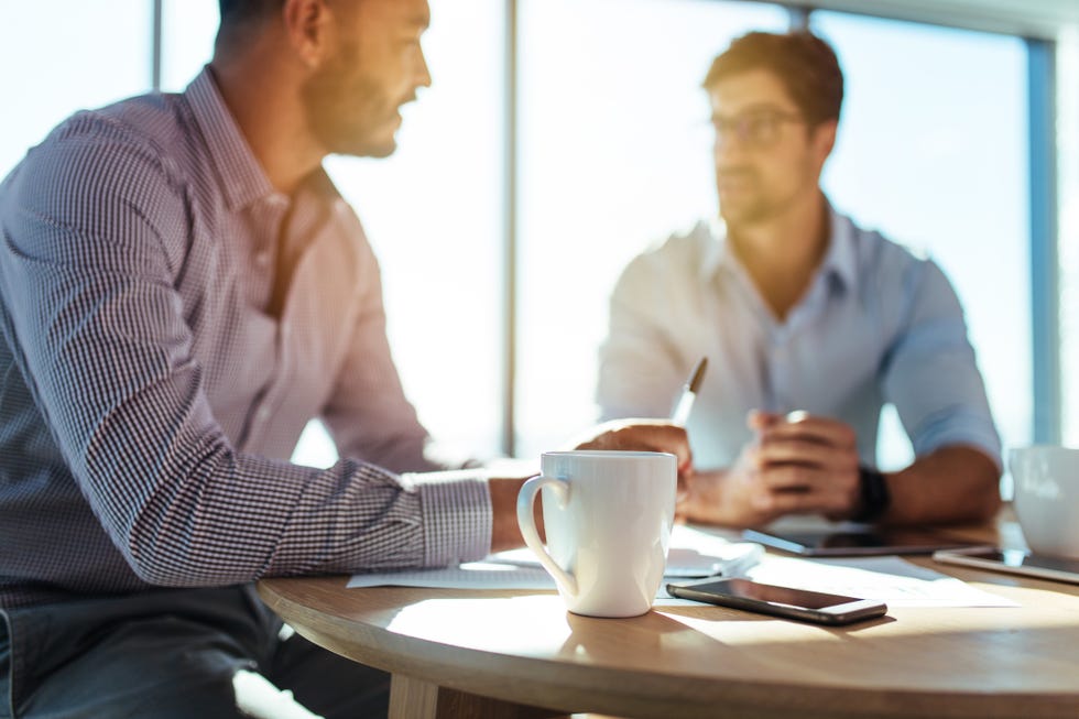 Business investors discussing business matters sitting at table in office.