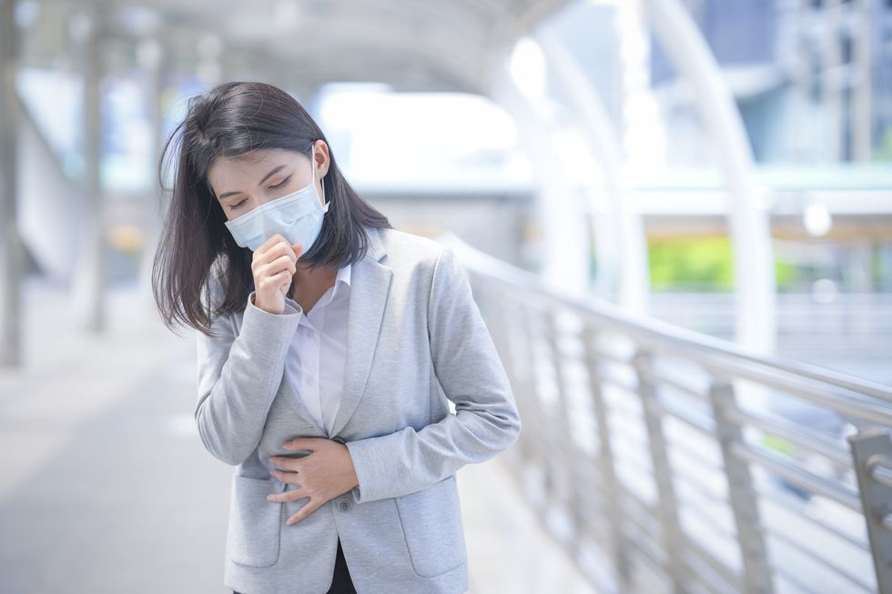 business woman wear face mask and coughing while standing in the town