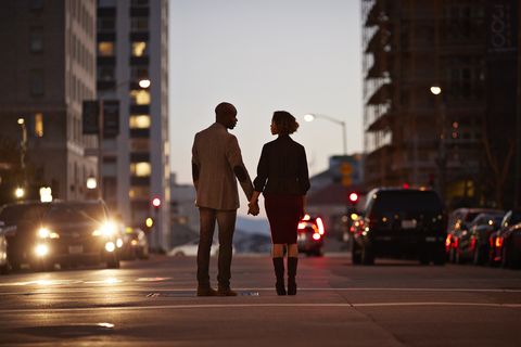 businessman and businesswoman standing on san francisco street and holding hands at night