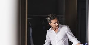 businessman at home getting dressed choosing shirt from wardrobe