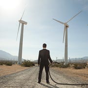Businessman at wind farm with gas pump businessman at wind farm with gas pump