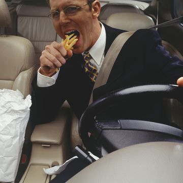 businessman devouring fries whilst driving car