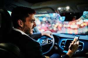 businessman looking at smartphone in car before departing on evening commute