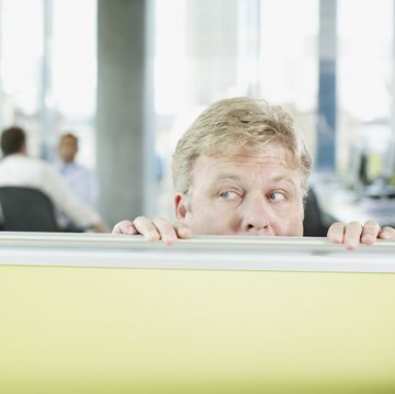 businessman peering over cubicle wall
