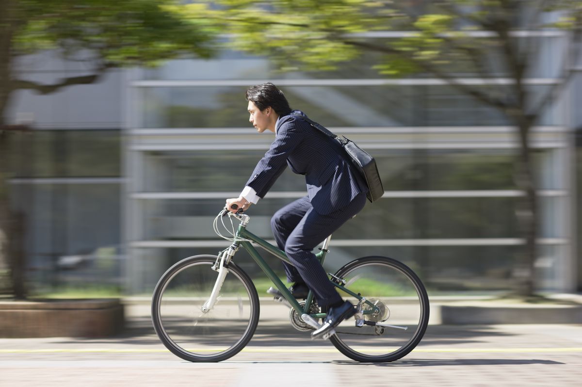 Businessman riding bike, side view
