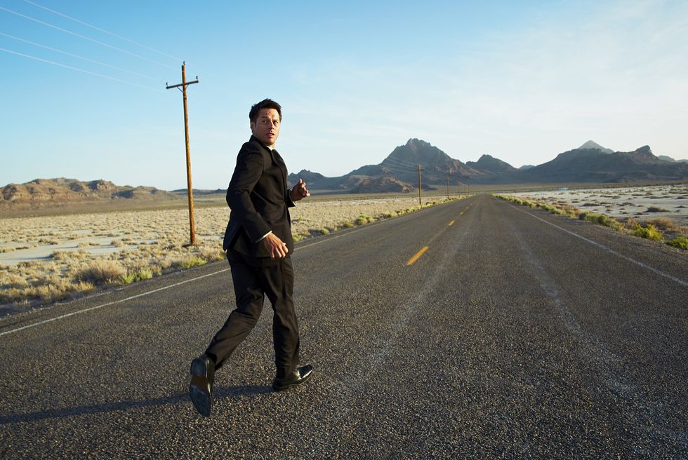 businessman running down desert road, looking back