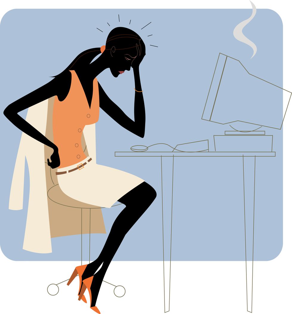 Businesswoman at computer with hand on forehead, side view