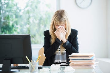 Businesswoman blowing nose in office