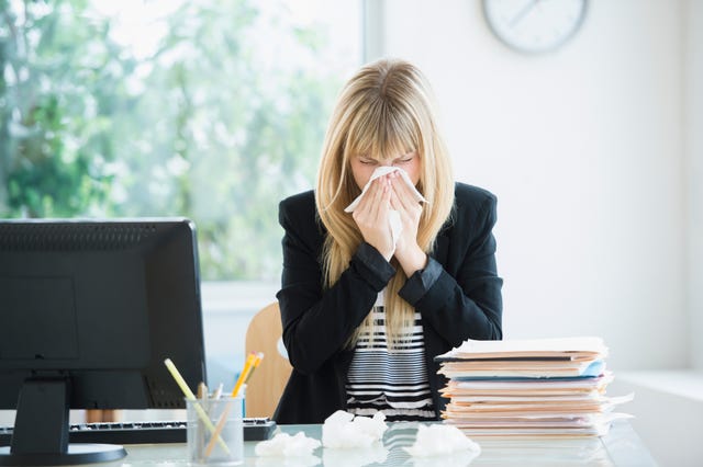 Businesswoman blowing nose in office
