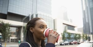 Businesswoman drinking coffee on city street