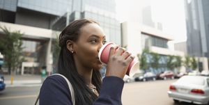 Businesswoman drinking coffee on city street