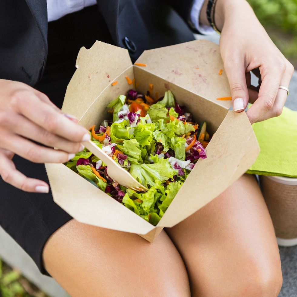 Businesswoman having lunch outdoors, partial view