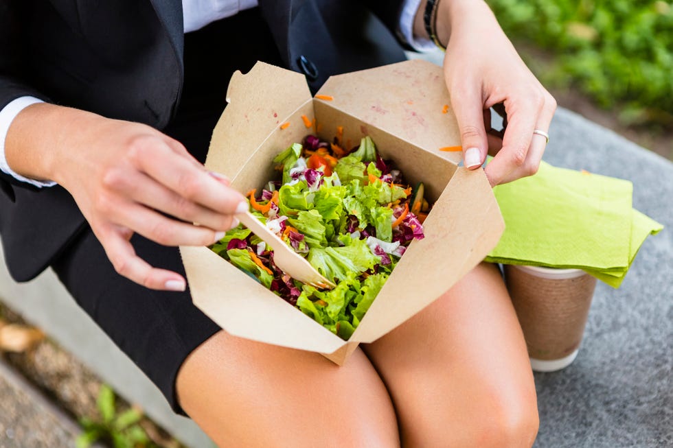 Businesswoman having lunch outdoors, partial view