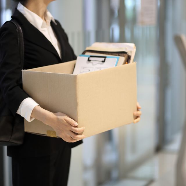businesswoman leaving office with box of personal items