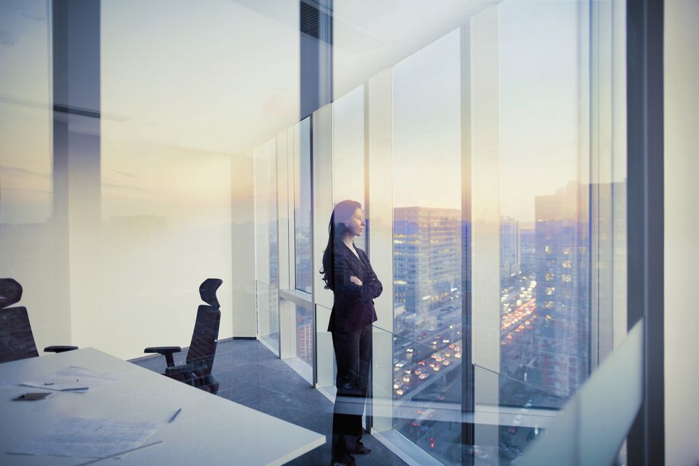 businesswoman looking out window in meeting room