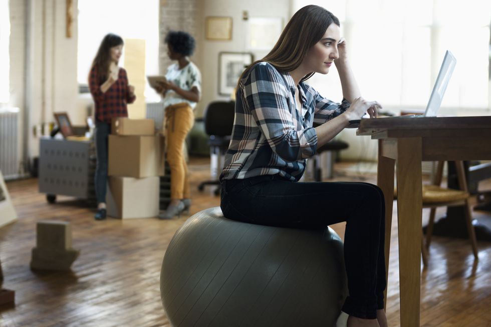 businesswoman sitting on fitness ball using laptop