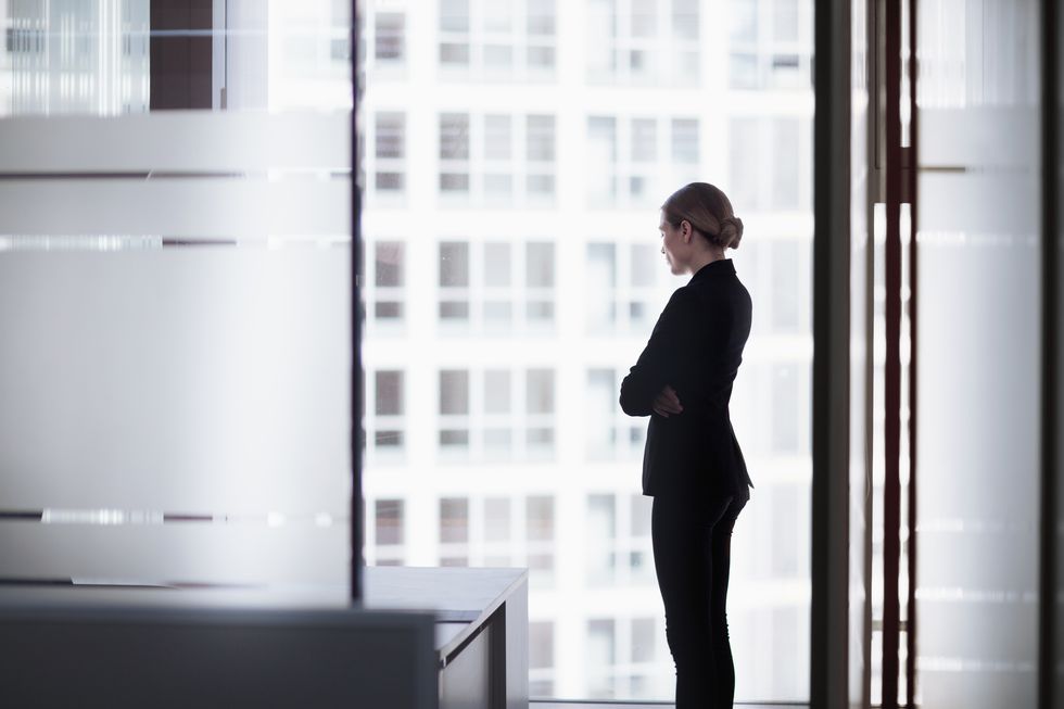 businesswoman standing looking out office window
