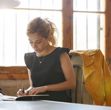 businesswoman writing in book at desk