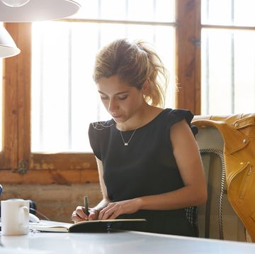 businesswoman writing in book at desk