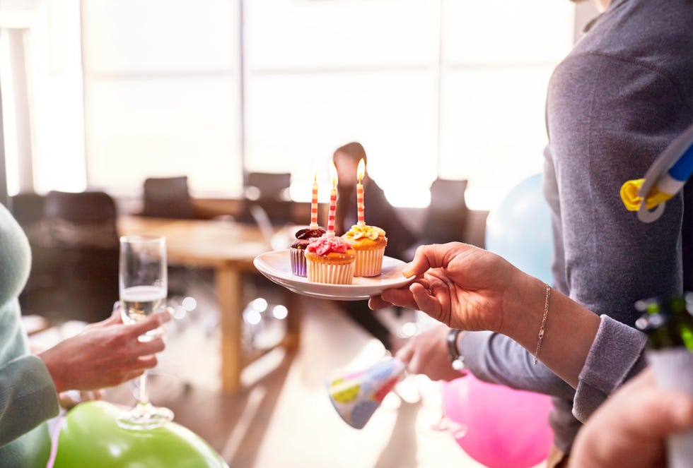Businesswomen surprising coworker with birthday cupcake in conference room
