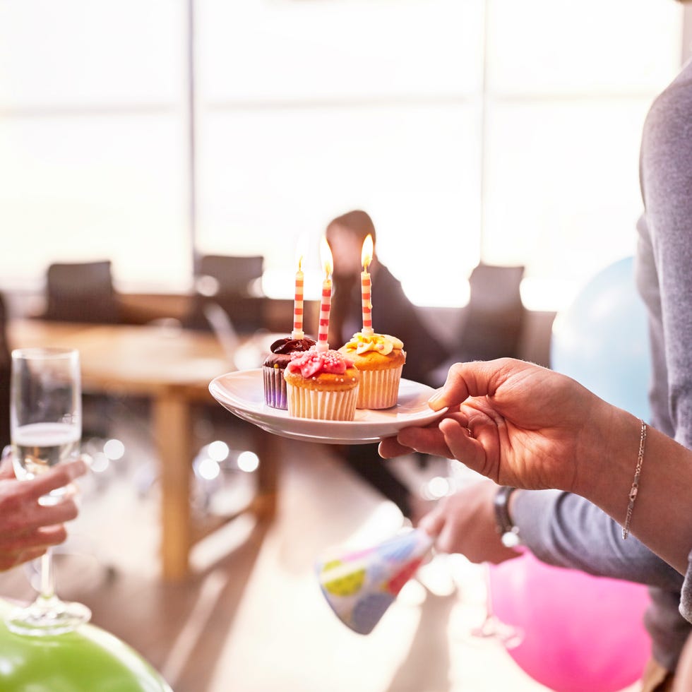 Businesswomen surprising coworker with birthday cupcake in conference room Businesswomen surprising coworker with birthday cupcake in conference room