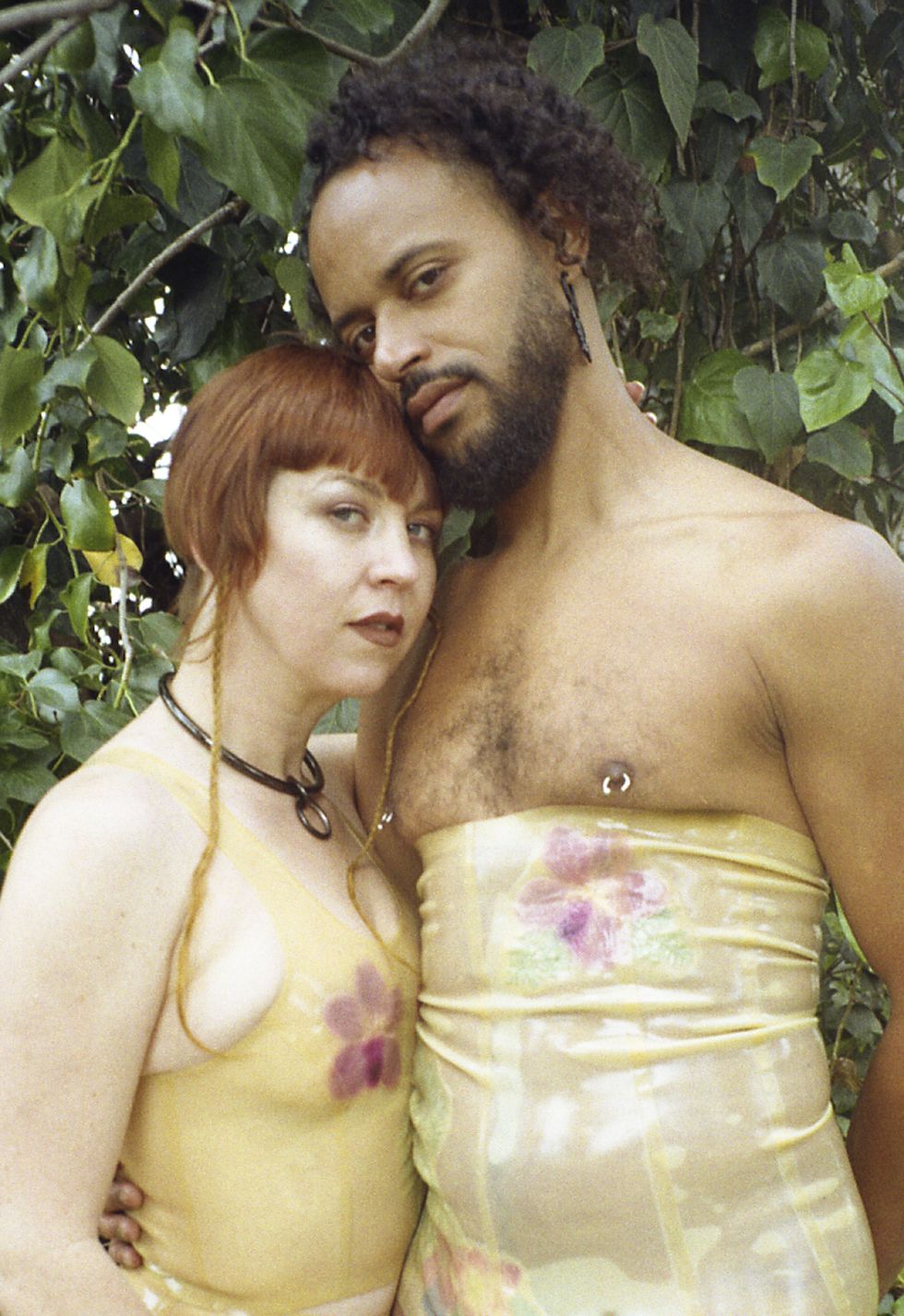 a man and a woman in bdsm attire gazing at the camera and embracing